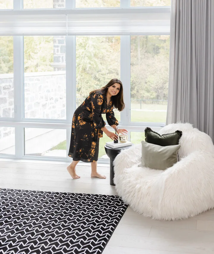 Ravi Gill arranging a staged living room with a white boucle chair, black and white rug and large windows